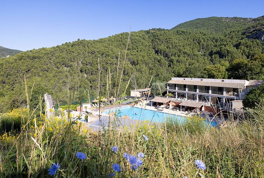 Piscine d’un camping entourée de collines boisées dans la Drôme, parfait pour des vacances nature en famille